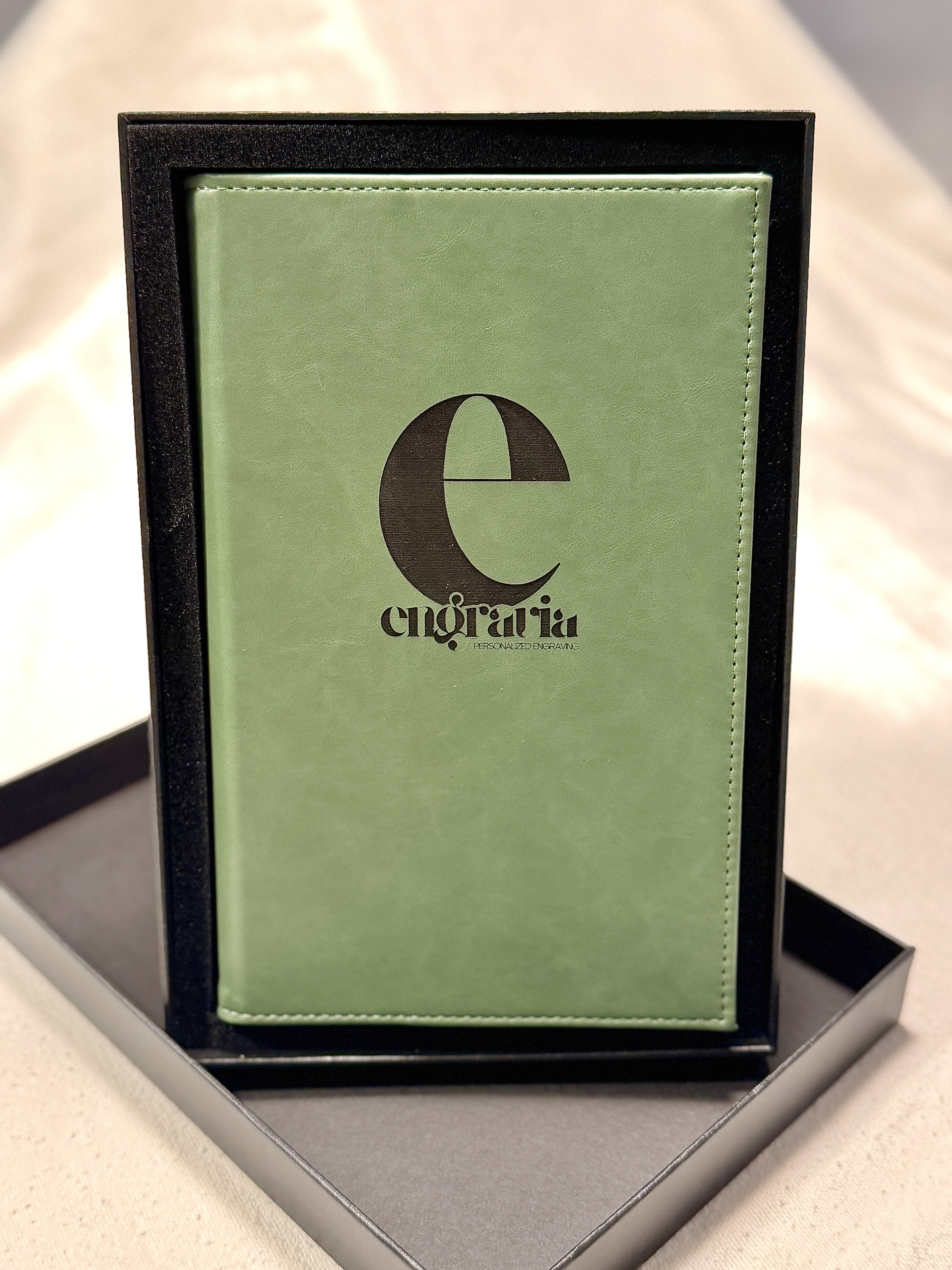 Green leatherette journal engraved with a customer logo, in its gift box.