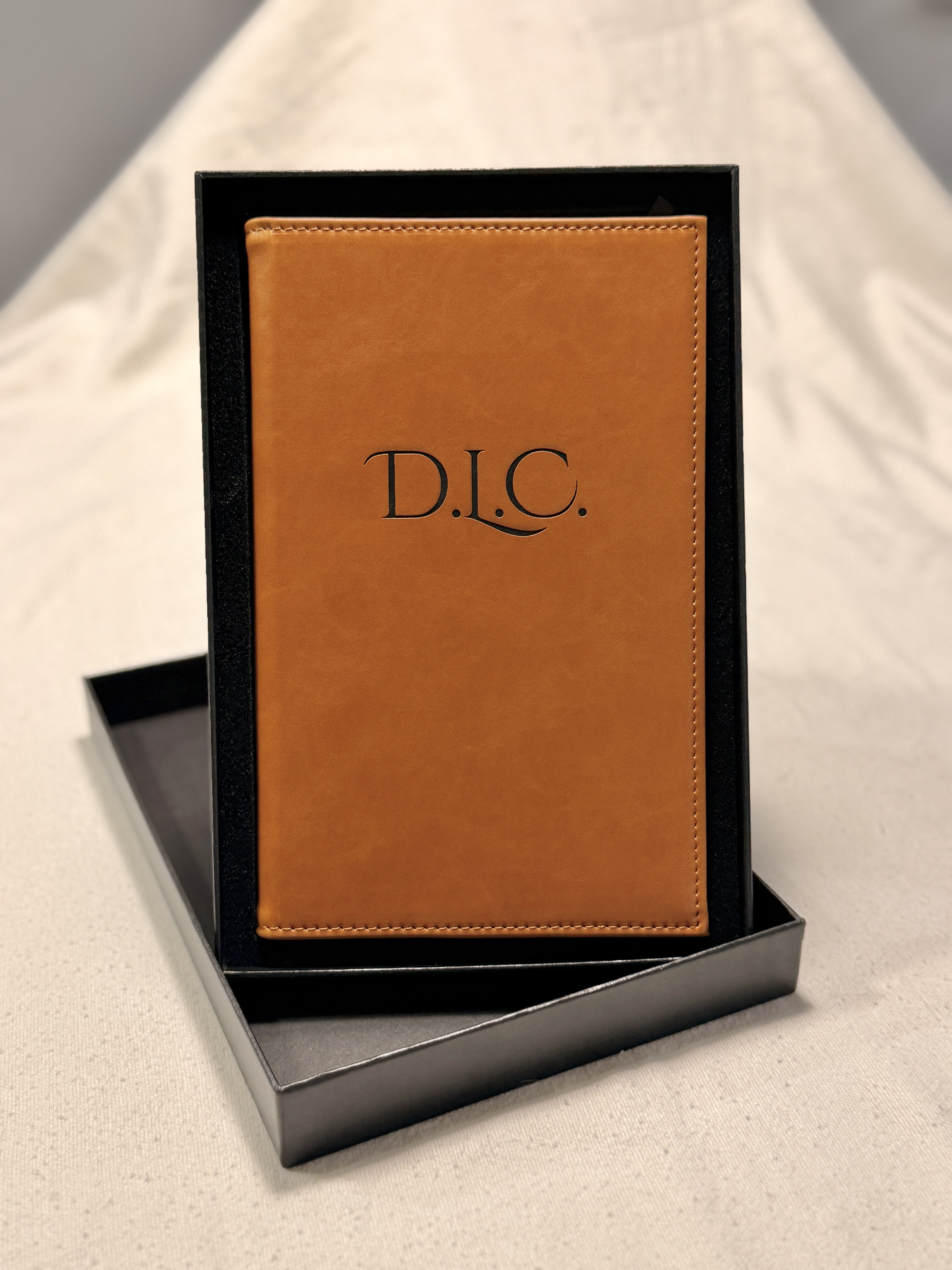 Tan leatherette journal engraved with a monogram, in its gift box.